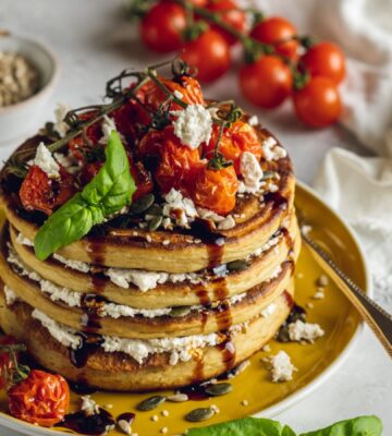 a stack of savory and vegan almond ricotta pancakes topped with cherry tomatoes and balsamic glaze