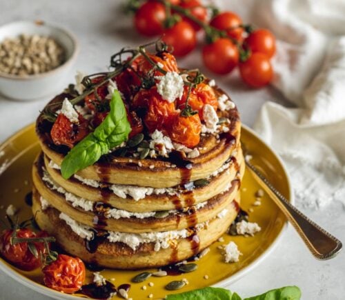 a stack of savory and vegan almond ricotta pancakes topped with cherry tomatoes and balsamic glaze