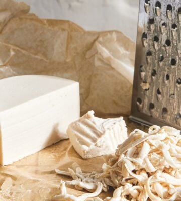 a picture of a block of basic melty cheese next to a cheese grater