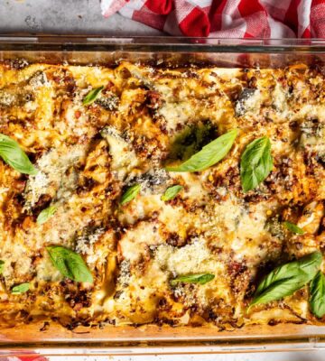 a baked cabbage and walnut lasagna in a dish with basil on top