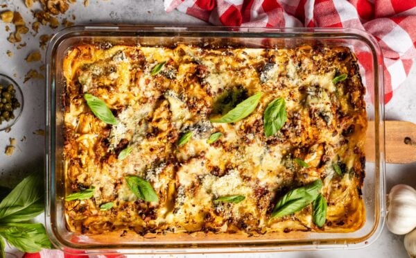 a baked cabbage and walnut lasagna in a dish with basil on top