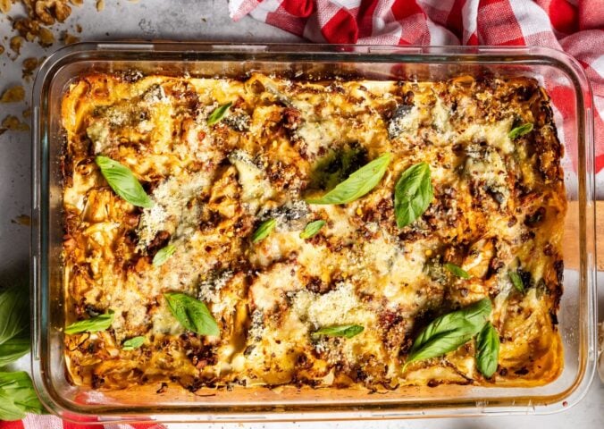 a baked cabbage and walnut lasagna in a dish with basil on top