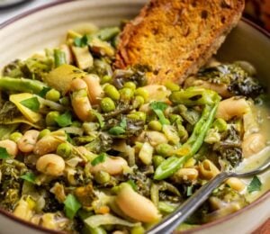 A bowl of green cannellini bean stew in a bowl with toasted bread