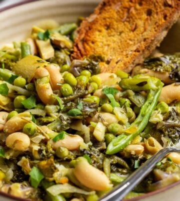 A bowl of green cannellini bean stew in a bowl with toasted bread