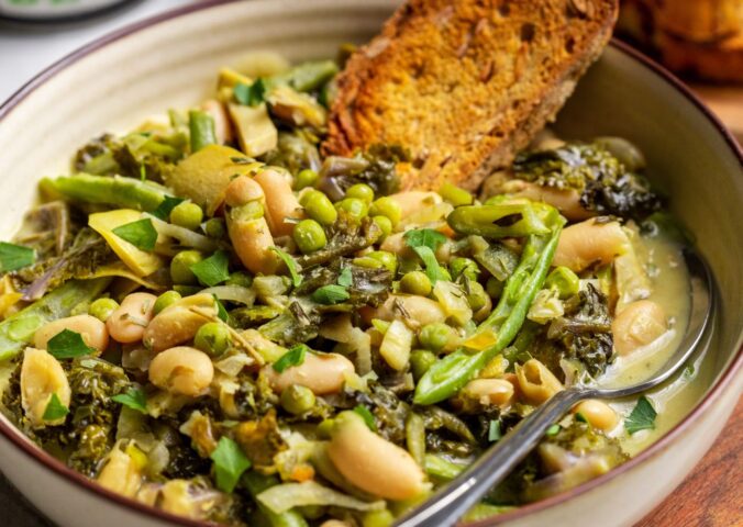 A bowl of green cannellini bean stew in a bowl with toasted bread