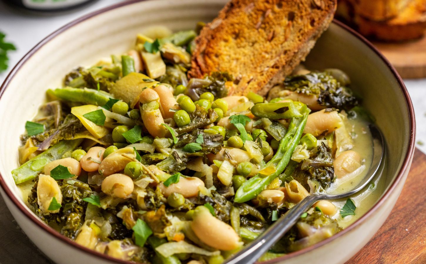 A bowl of green cannellini bean stew in a bowl with toasted bread