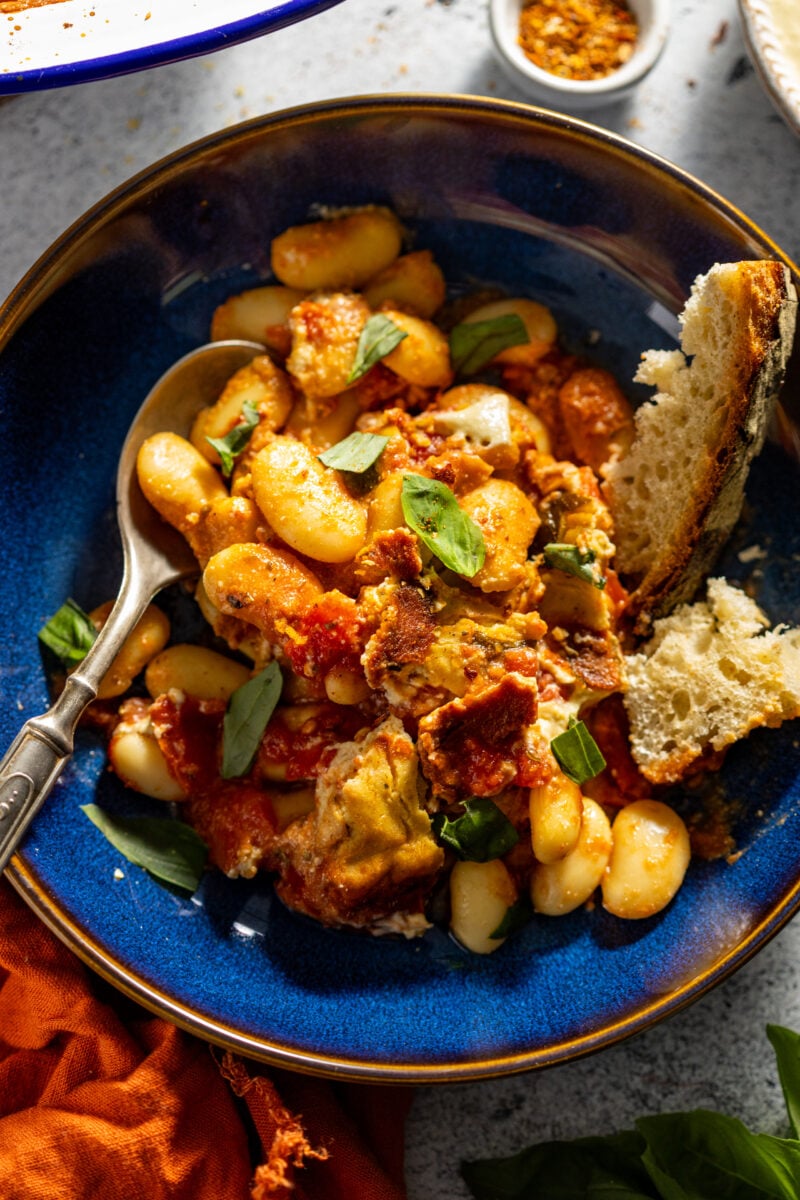 a bowl full of caprese bean bake made with a cheesy bean and cashew sauce