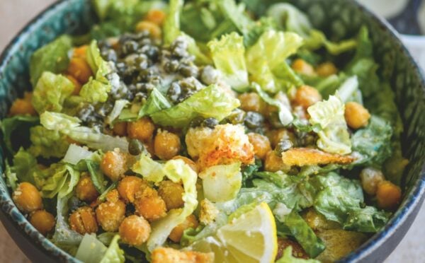 a bowl of vegan chickpea Caesar salad with chickpeas, capers, lemon, and croutons