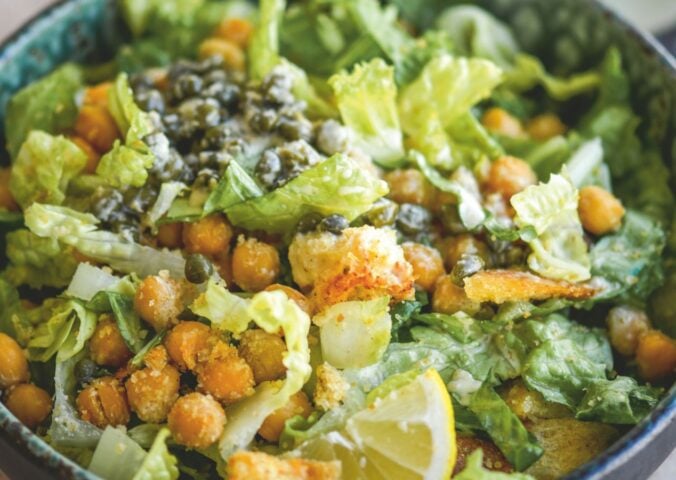 a bowl of vegan chickpea Caesar salad with chickpeas, capers, lemon, and croutons