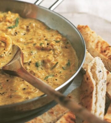 a pan of coconut dhal with toasted naan fingers on the side