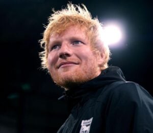 Singer Ed Sheeran looking past the camera in front of a black background