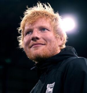 Singer Ed Sheeran looking past the camera in front of a black background