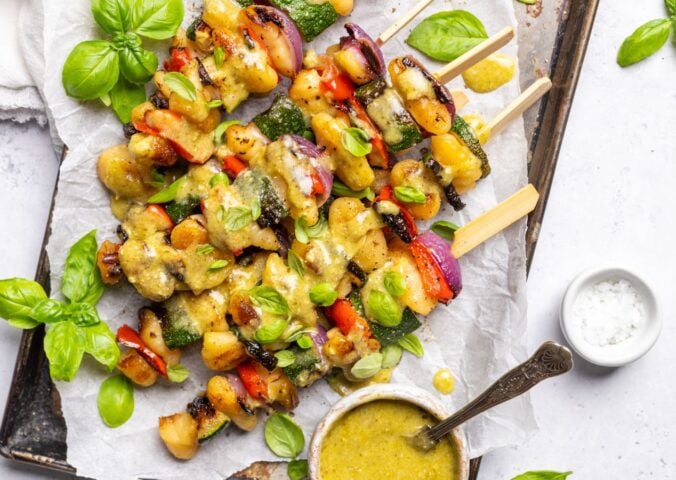 a tray of grilled gnocchi skewers with basil dip
