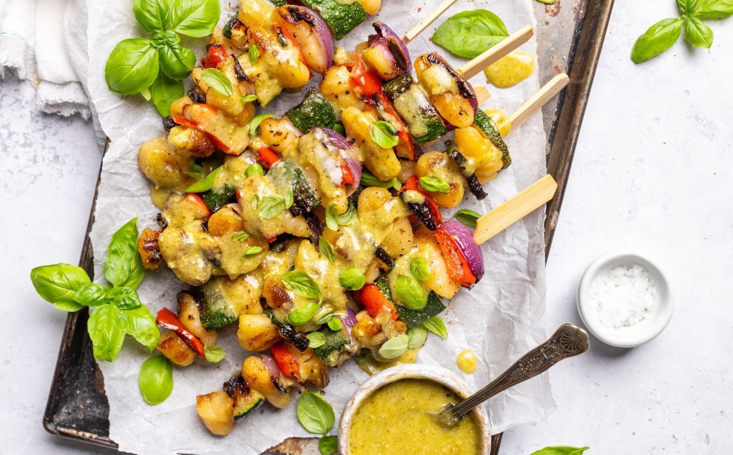 a tray of grilled gnocchi skewers with basil dip