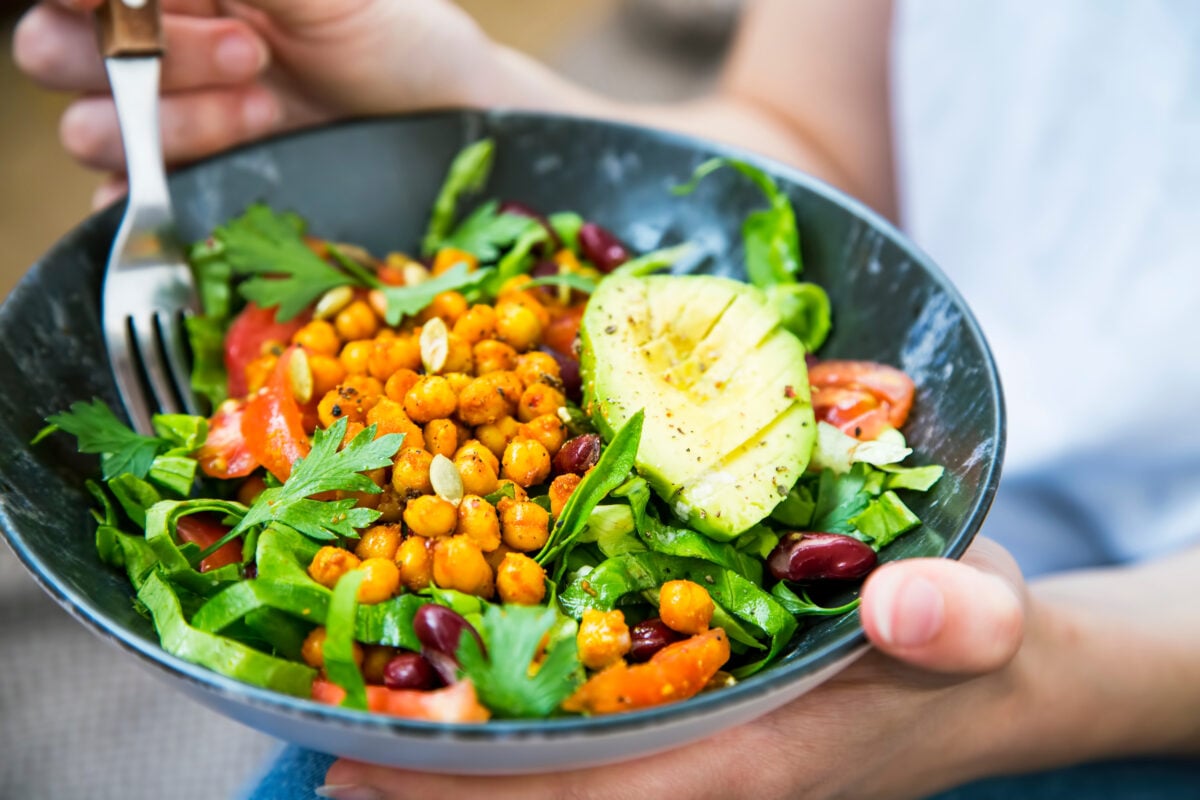 A bowl full of health plant-based foods like avocado, chickpeas, and rocket