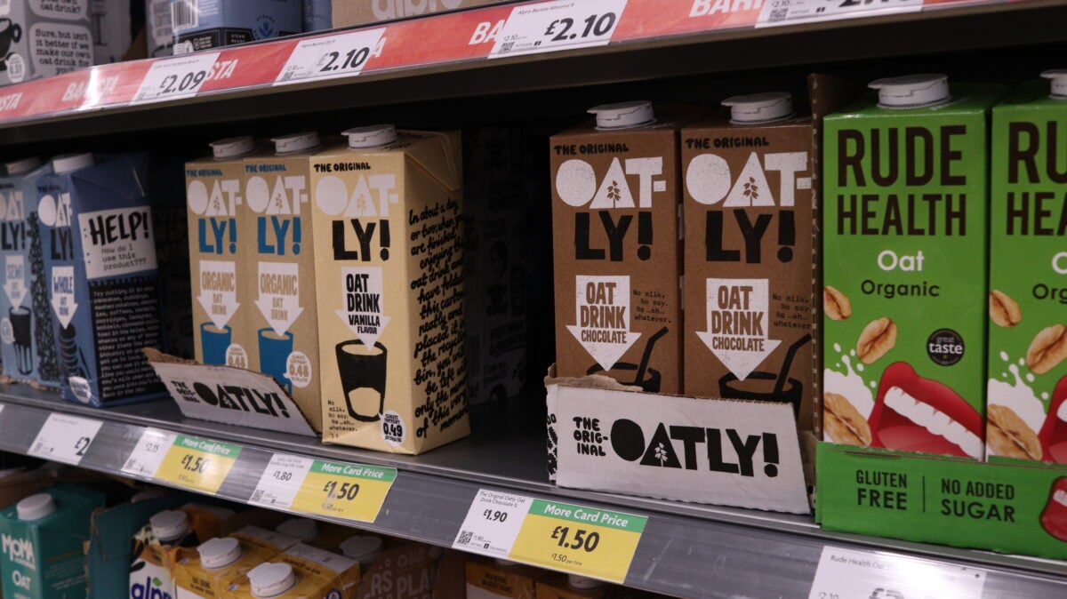 Photo shows a selection of plant milks on supermarket shelves, including Oatly and Rude Health