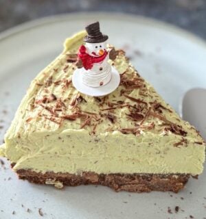 A vegan pistachio cheesecake with a snowman on top