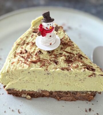 A vegan pistachio cheesecake with a snowman on top