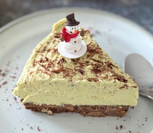 A vegan pistachio cheesecake with a snowman on top