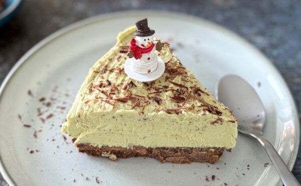 A vegan pistachio cheesecake with a snowman on top