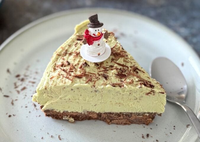 A vegan pistachio cheesecake with a snowman on top