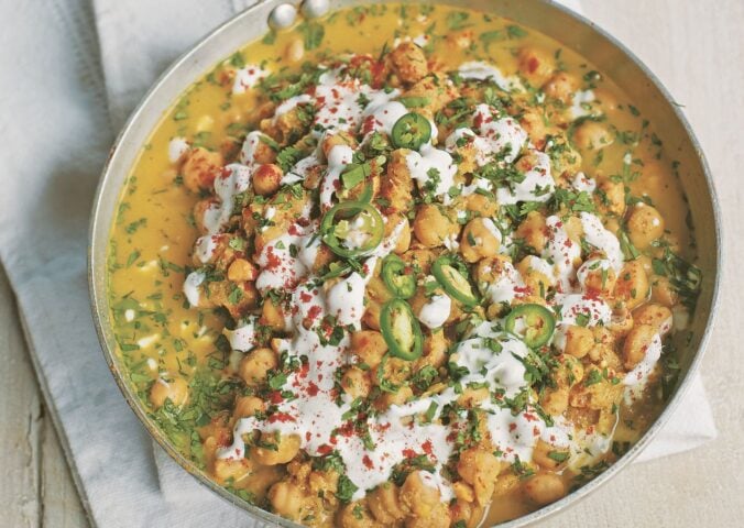 a pan of spicy chickpea curry with soya yogurt, fresh green chili, and chickpeas