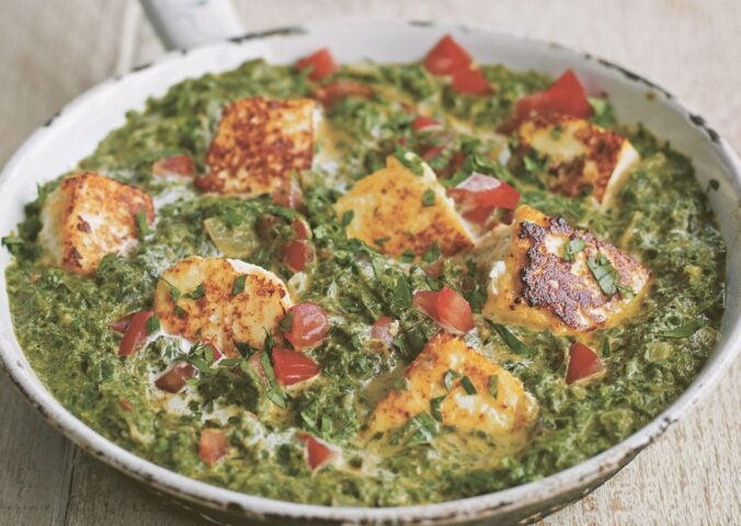 a pan of spinach tomato and tofu curry made with chili and plant-based cream