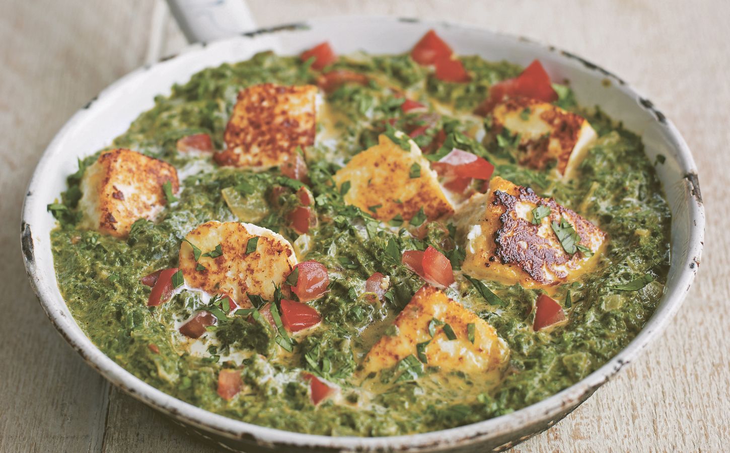 a pan of spinach tomato and tofu curry made with chili and plant-based cream