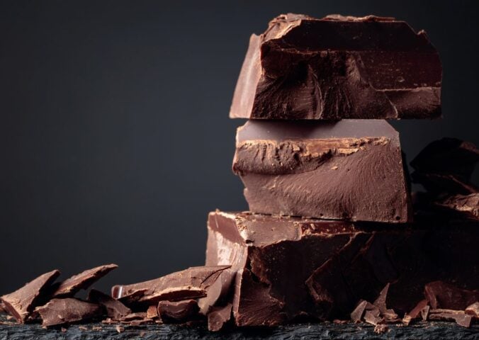 A pile of dark chocolate, which is associated with lowered type 2 diabetes risk, in front of a dark background