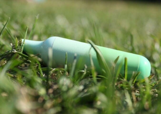 A green disposable vape in the grass