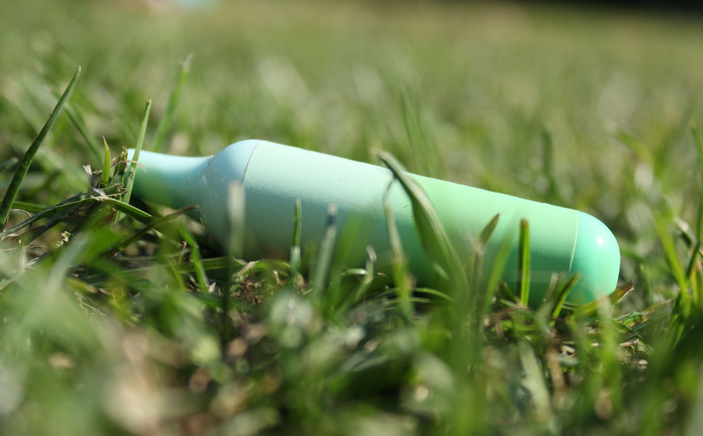 A green disposable vape in the grass