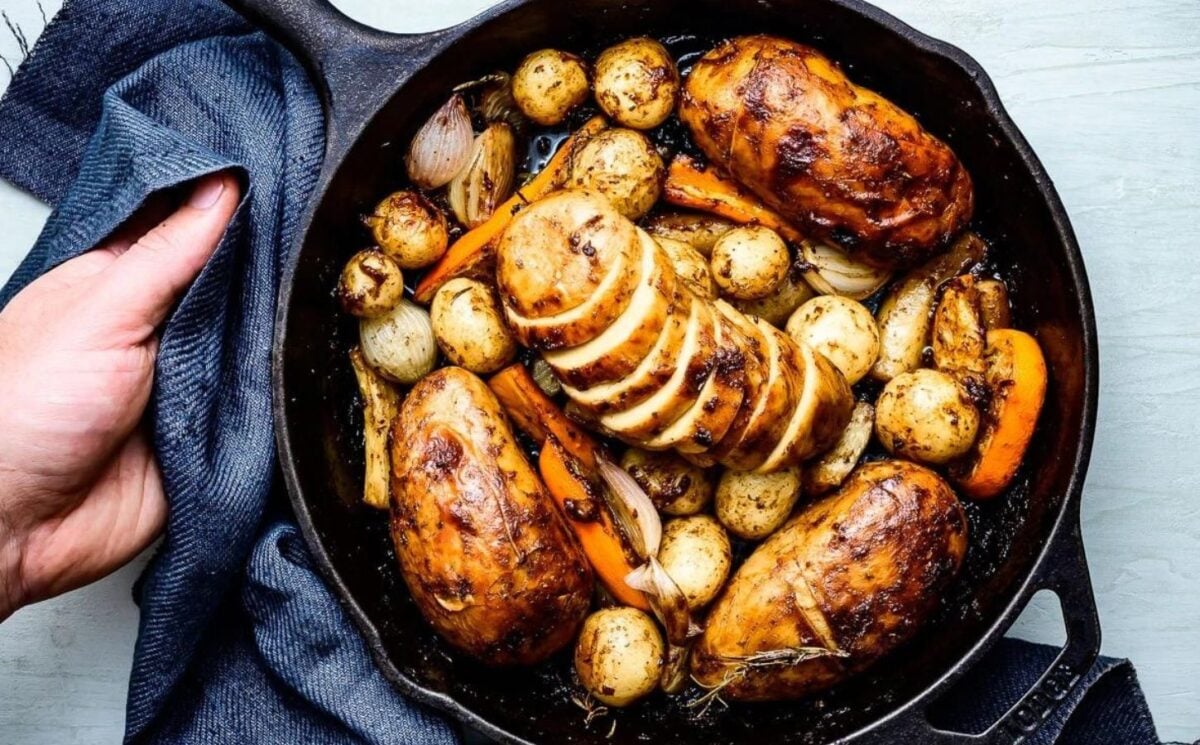 a cast iron skillet full of roasted potatoes, carrots, garlic, and carefully arranged vegan chicken, part of vegan centerpieces to serve at your Christmas party