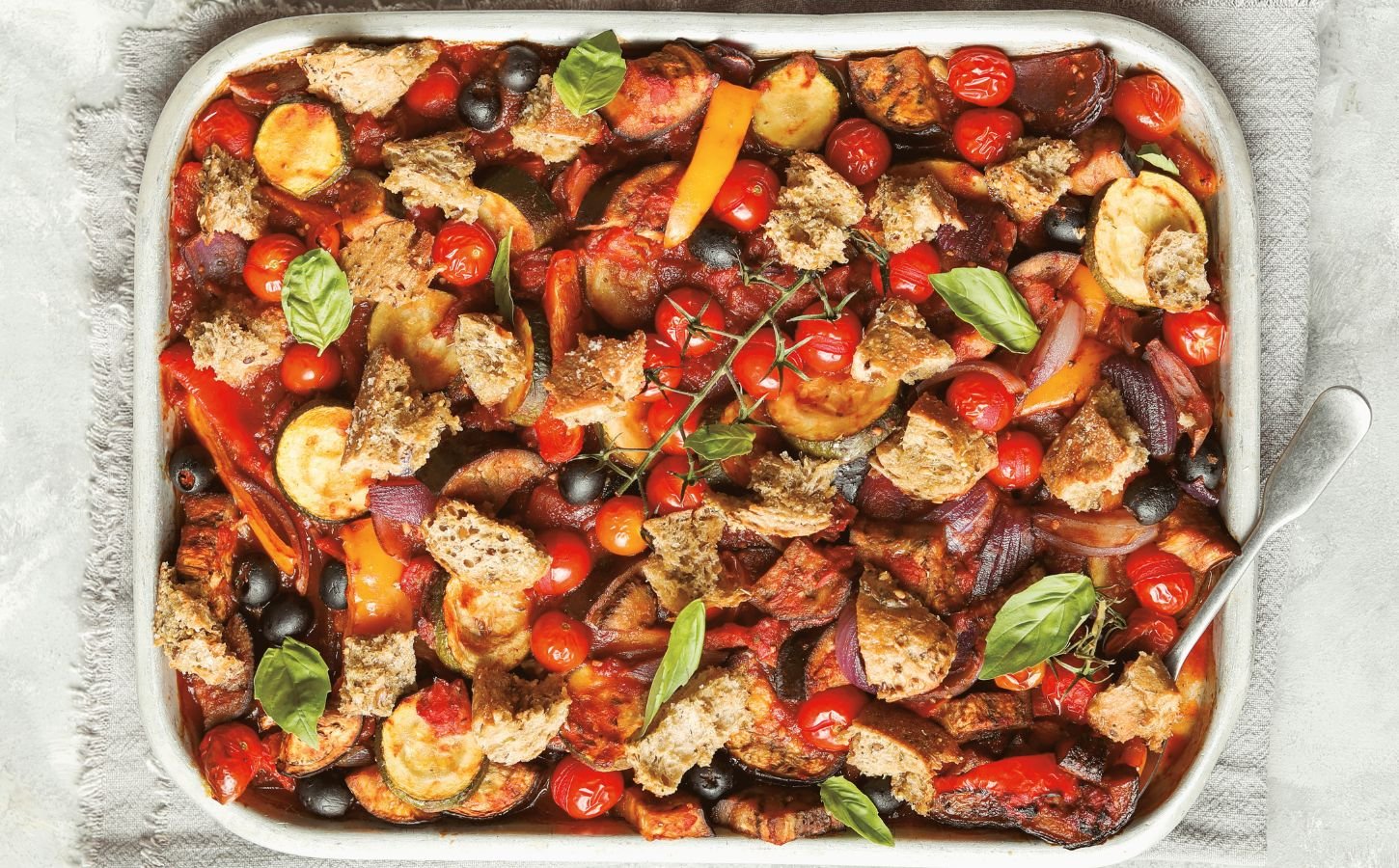 an Italian veggie sheet bake with eggplant, zucchini, olives, tomato, and bread