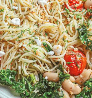 a bowl of angel hair with lemon kale and tomatoes with vegan feta