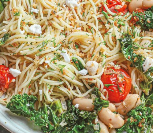 a bowl of angel hair with lemon kale and tomatoes with vegan feta