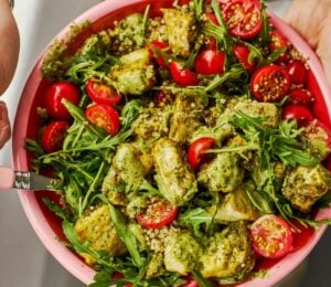 a baked pesto tofu bro bowl with tofu, quinoa, cherry tomatoes and rocket