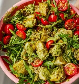 a baked pesto tofu bro bowl with tofu, quinoa, cherry tomatoes and rocket