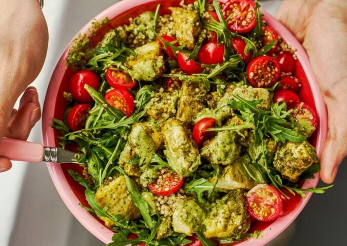 a baked pesto tofu bro bowl with tofu, quinoa, cherry tomatoes and rocket