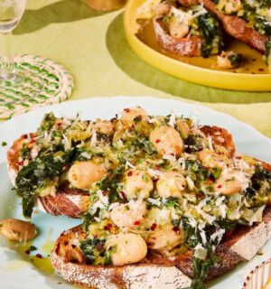 two plates of boozy butter beans and greens with spinach, mustard, and vegan parmesan