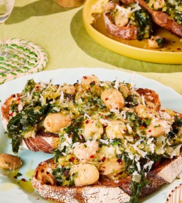 two plates of boozy butter beans and greens with spinach, mustard, and vegan parmesan