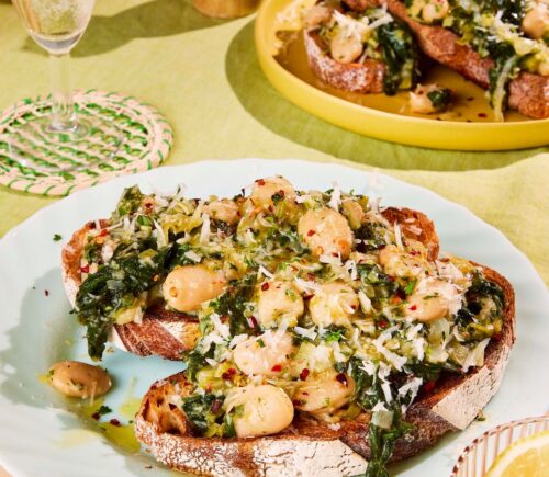 two plates of boozy butter beans and greens with spinach, mustard, and vegan parmesan