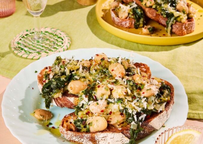 two plates of boozy butter beans and greens with spinach, mustard, and vegan parmesan