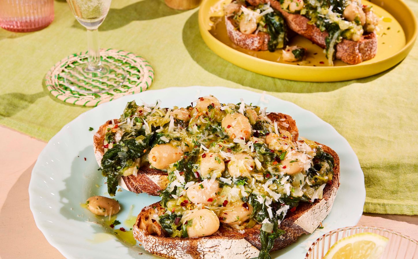 two plates of boozy butter beans and greens with spinach, mustard, and vegan parmesan