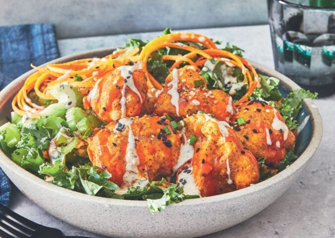 one of the buffalo cauliflower wings bowls with kale, hemp hearts, and sesame seeds