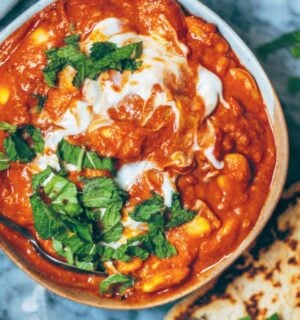 A bowl of vegan butter bean curry next to some naan