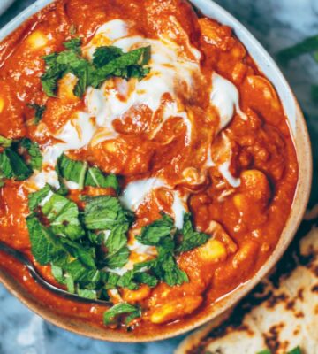 A bowl of vegan butter bean curry next to some naan