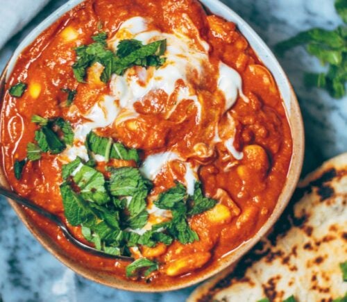 A bowl of vegan butter bean curry next to some naan