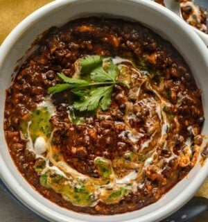 a bowl of buttery black dhal, a vegan dish served with poppadom