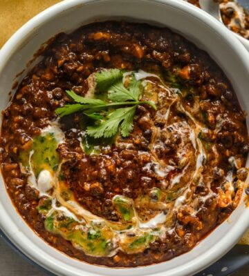 a bowl of buttery black dhal, a vegan dish served with poppadom