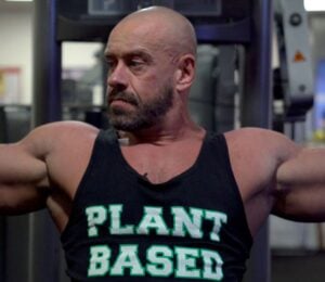 Vegan athlete Hench Herbivore wearing a vest top saying "Plant Based" while at the gym